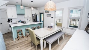 A modern kitchen with white cabinets, a central island, bar stools, and pendant lighting. - FREE Heated Pool! Sleeps 14 with Game Room! Close to Pier Park, Beaches & 30A! (Panama City Beach)