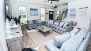 A modern living room with a grey sofa set, a coffee table, and a view of the outside. - FREE Heated Pool! Sleeps 14 with Game Room! Close to Pier Park, Beaches & 30A! (Panama City Beach)