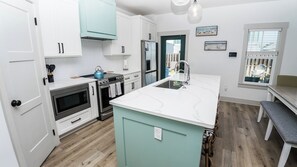 A modern kitchen with white cabinets, a teal island, and a stainless steel refrigerator. - FREE Heated Pool! Sleeps 14 with Game Room! Close to Pier Park, Beaches & 30A! (Panama City Beach)