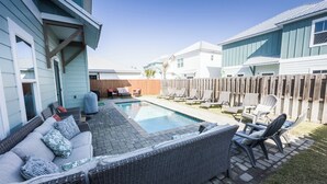 A backyard with a swimming pool, a covered seating area, and a wooden fence.