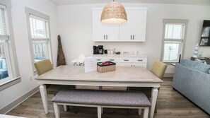 A modern kitchen with white cabinetry, a dining table with benches, and a hanging light fixture. - FREE Heated Pool! Sleeps 14 with Game Room! Close to Pier Park, Beaches & 30A! (Panama City Beach)