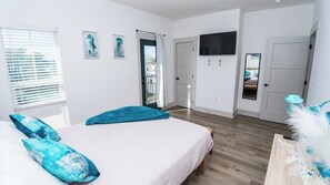 A bedroom with a bed, a television, and a door leading to a balcony. - FREE Heated Pool! Sleeps 14 with Game Room! Close to Pier Park, Beaches & 30A! (Panama City Beach)