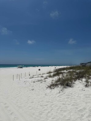Una playa con cielo despejado, orilla arenosa y una valla al frente.