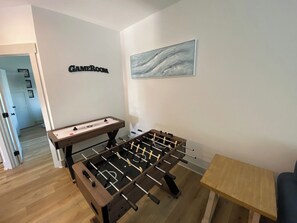 A room with two foosball tables, a wooden table, and a wall-mounted sign. - FREE Heated Pool! Sleeps 14 with Game Room! Close to Pier Park, Beaches & 30A! (Panama City Beach)