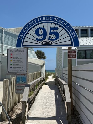 A beach access sign with a warning flag system and a wooden walkway leading to the beach. - FREE Heated Pool! Sleeps 14 with Game Room! Close to Pier Park, Beaches & 30A! (Panama City Beach)