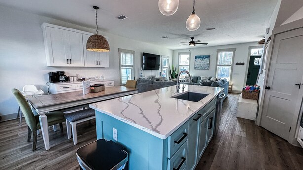A modern kitchen with a large island, white cabinets, and a dining area with a table and chairs.