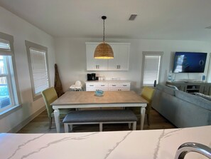 A modern kitchen with a dining table, chairs, a hanging light fixture, and a television. - FREE Heated Pool! Sleeps 14 with Game Room! Close to Pier Park, Beaches & 30A! (Panama City Beach)