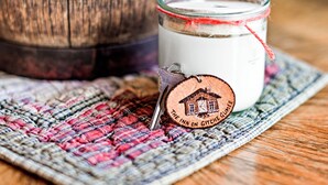 Un pot contenant une bougie blanche, orné d’une étiquette sur laquelle on peut lire « The Inn on Gitche Gumee », le tout posé sur un set de table en fibres tressées.