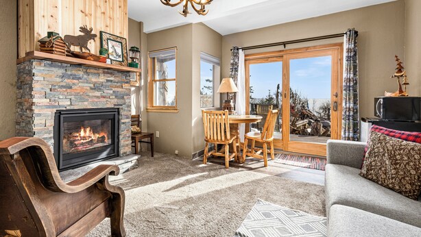 Un salon chaleureux avec une cheminée, des meubles en bois et une vue sur l’extérieur.