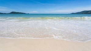 A beach with clear blue water and a sandy shore.