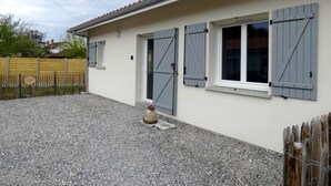 A building with a gravel driveway, a wooden fence, and a small decorative item in the center. - La scierie - SABRES - Gîte (SABRES)