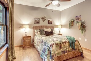 A bedroom with a large bed, two bedside tables, a ceiling fan, and wall-mounted plants. - Lake Views & Golf Access at Secluded Drasco Lodge (Drasco)