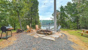 An outdoor seating area with Adirondack chairs, a grill, and a stone fire pit. - Lake Views & Golf Access at Secluded Drasco Lodge (Drasco)