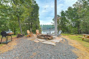 An outdoor seating area with Adirondack chairs, a grill, and a stone fire pit. - Lake Views & Golf Access at Secluded Drasco Lodge (Drasco)