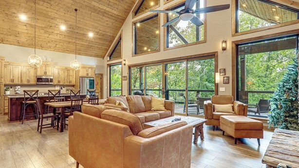 A spacious living area with a large wooden ceiling, a modern kitchen, and large windows offering a view of the outdoors. - Lake Views & Golf Access at Secluded Drasco Lodge (Drasco)