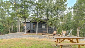 A cabin with a deck, surrounded by trees, and a picnic table in the foreground. - Lake Views & Golf Access at Secluded Drasco Lodge (Drasco)