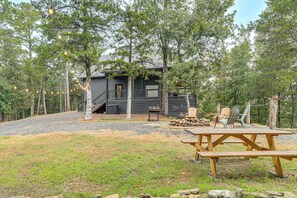 A cabin with a deck, surrounded by trees, and a picnic table in the foreground. - Lake Views & Golf Access at Secluded Drasco Lodge (Drasco)