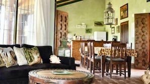 Una sala de estar acogedora con un sofá negro, una mesa de centro redonda y un comedor con sillas de madera y una mesa.