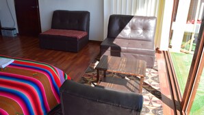 A living room with a sofa, a coffee table, and a patterned rug. - INTI TITIKAKA (Puno)