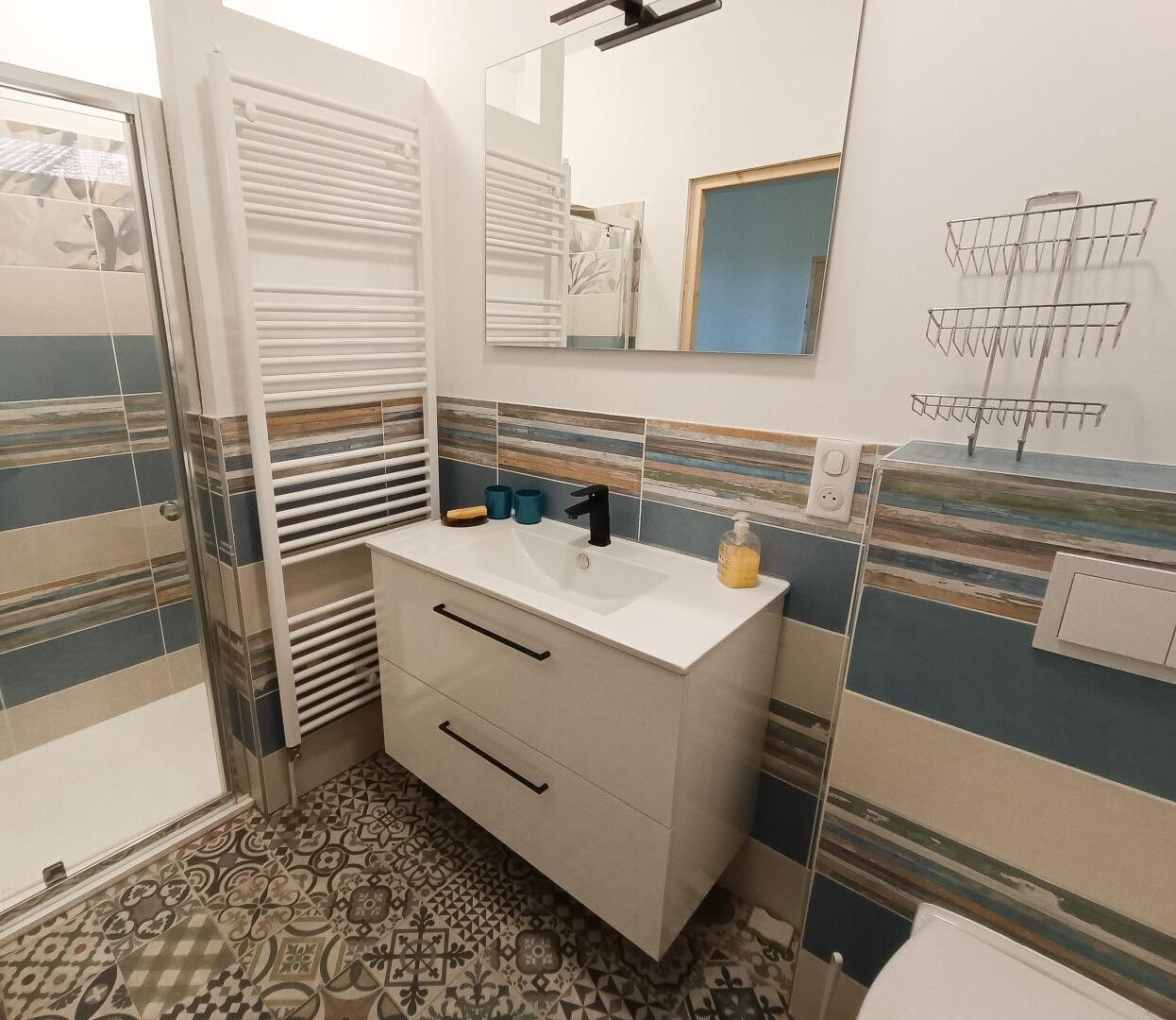 A bathroom with a white sink, a mirror, and a patterned floor.
