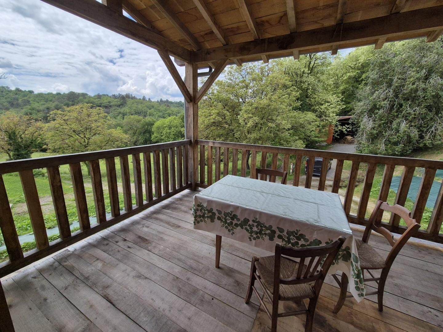 Eine Holzterrasse mit Tisch und Stühlen mit Blick auf eine üppige grüne Landschaft.