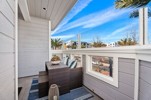 A balcony with a wicker sofa, a potted plant, and a view of a street and buildings. - LOCATION! WALK to Fabulous Dana Point Harbor! Newly remodeled & Furnished !! (Dana Point)