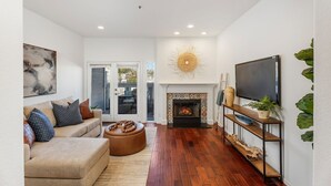 Ein modernes Wohnzimmer mit Kamin, einer Couch, einem Couchtisch und einem Fernseher auf einem Lowboard.