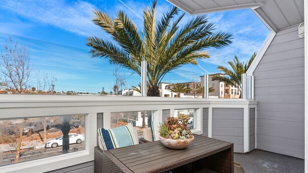 Ein Balkon mit Korbmöbeln, einem Blumentopf und Blick auf die Nachbarschaft.