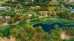 Vista aérea de un campo de golf con múltiples zonas verdes, búnkeres de arena y un estanque.
