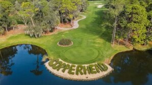 Campo de golf con un estanque identificado como "CUPPERHEAD" y follaje circundante.
