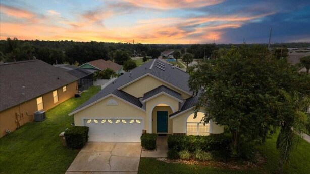 A residential house with a garage, a well-maintained lawn, and a driveway leading to the entrance. - Home w/Private Pool, Minutes from all Disney Parks (Kissimmee)