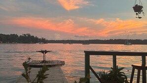 A wooden dock extending into calm water with boats in the distance, under a sunset sky. - Hostal Cay (Bastimentos)