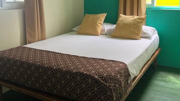 Una cama con colcha estampada, dos almohadas y cabecero de madera.