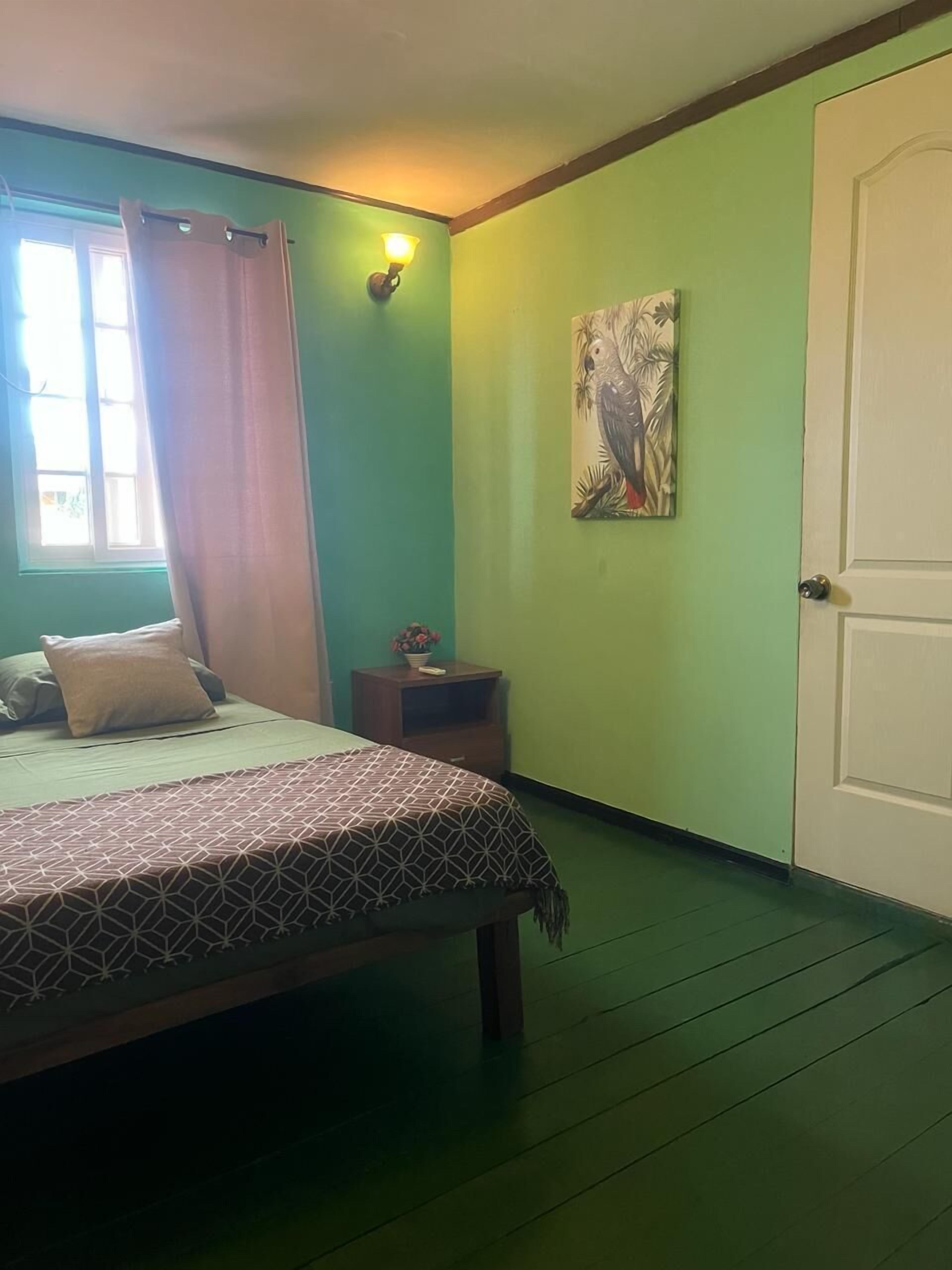 A room with a bed, a nightstand, a painting, and a door.