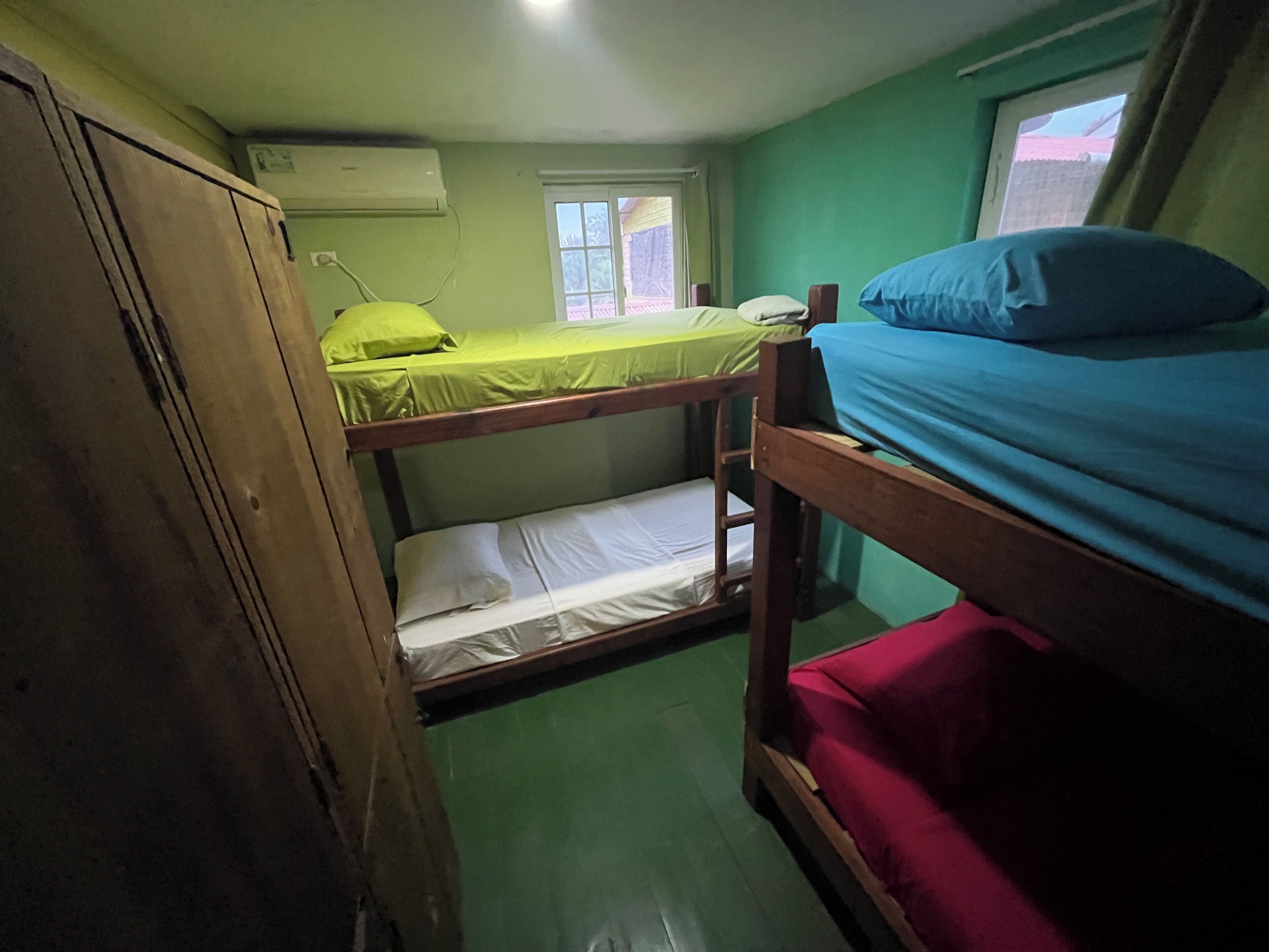A dormitory room with bunk beds, a window, and an air conditioning unit.