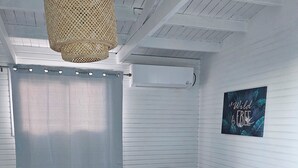 A bedroom with a bed, a ceiling fan, and a wall-mounted air conditioner.