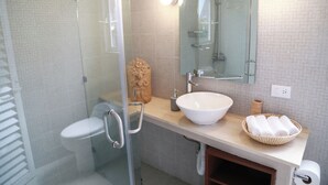 Ein modernes Badezimmer mit Duschkabine aus Glas, einem weißen Waschbecken und einem Spiegel darüber.
