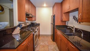 Una cocina compacta con armarios de madera, estufa, refrigerador y pileta.