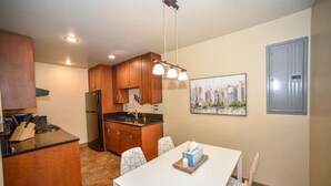 Una cocina compacta con armarios de madera, un refrigerador y una mesa de comedor con sillas.