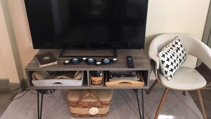Televisor de pantalla plana sobre un mueble de madera con un control remoto, un libro y una bandeja decorativa.