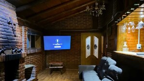 A cozy room with a brick fireplace, a television mounted on the wall, a wooden bench, and a cushioned seating area. - Cabañas Matlahuacales (Chignahuapan)