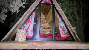 A triangular wooden structure with a door, possibly a cabin or hut, set in a forested area. - Cabañas Matlahuacales (Chignahuapan)