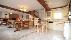 A spacious kitchen with wooden furniture, a staircase, and a dining area.