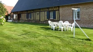 Ein traditionelles Fachwerkhäuschen mit gepflegtem Rasen und einer Sitzgelegenheit im Freien.