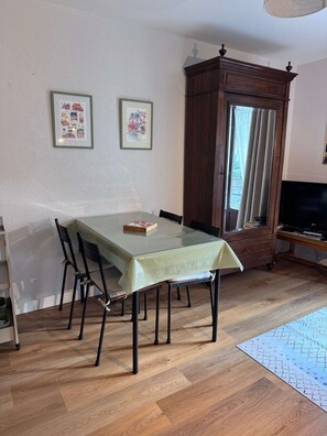 Ein Essbereich mit Tisch, Stühlen, einem Schrank und einem Fernseher.
