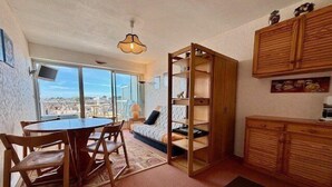 A cozy living area with a dining table, chairs, a sofa, and a built-in bookshelf.