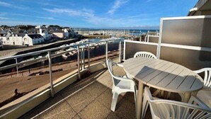 A balcony with a table and chairs overlooking a marina with boats.