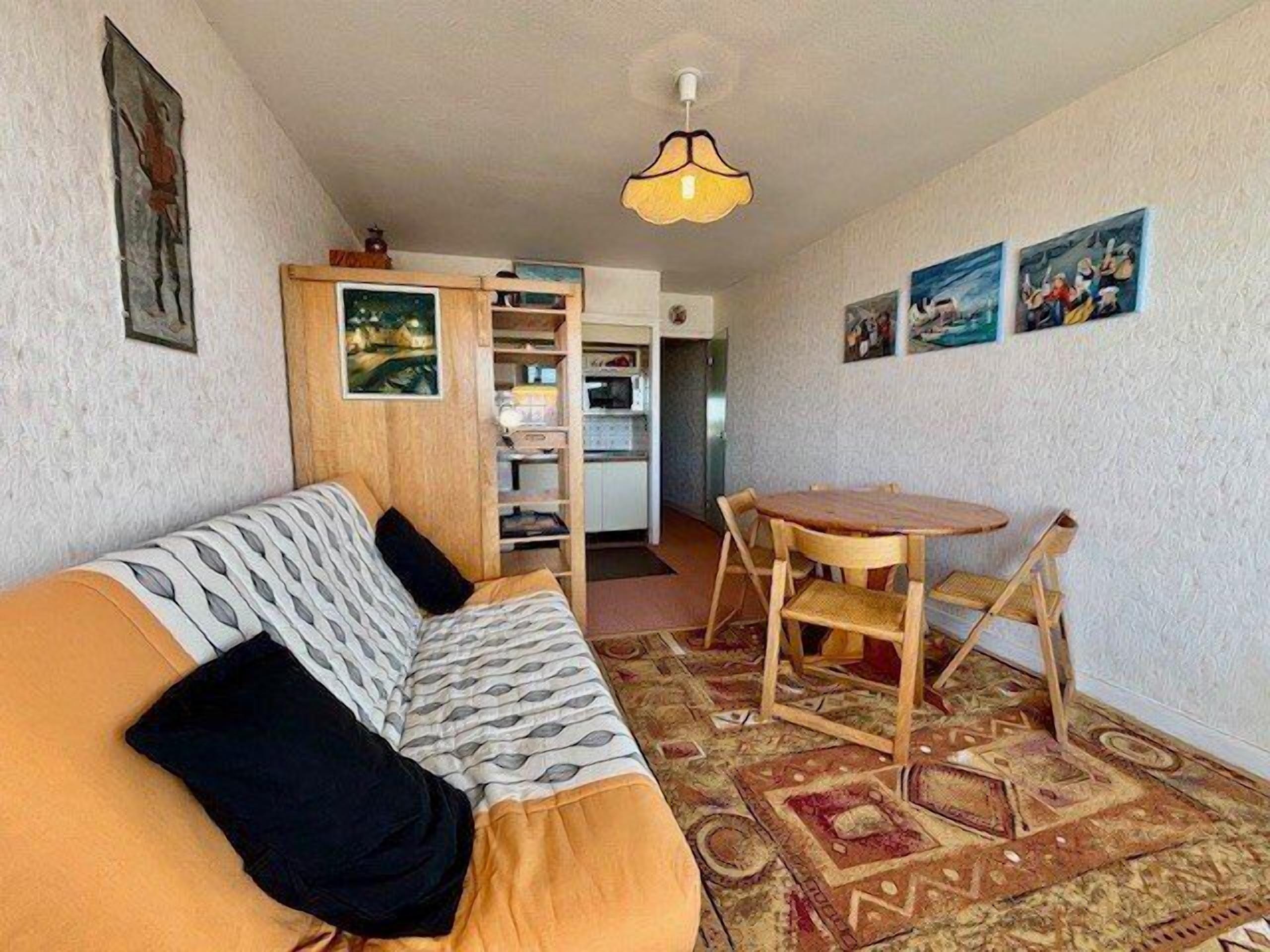 A compact living space with a sofa, a small dining table, and a kitchen area.