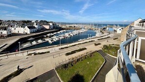 A marina with boats docked, a bridge, and buildings along the waterfront.