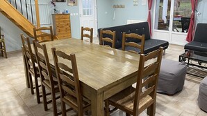 A dining area with a wooden table and chairs, a sofa, and a staircase. - Gîtes de France® - l'Humesnil (ST VICTOR L'ABBAYE)